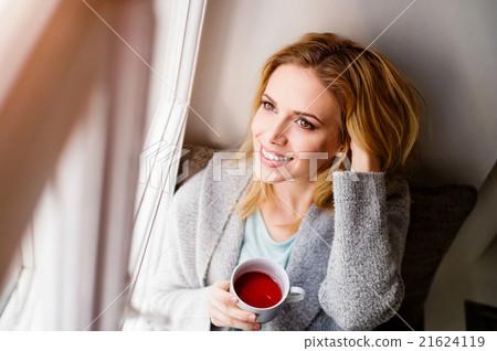 Woman on window sill holding a cup of tea 21624119