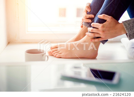 Feet of unrecognizable woman sitting on window 21624120