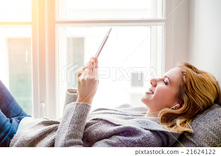 Woman lying on window sill with smartphone 21624122