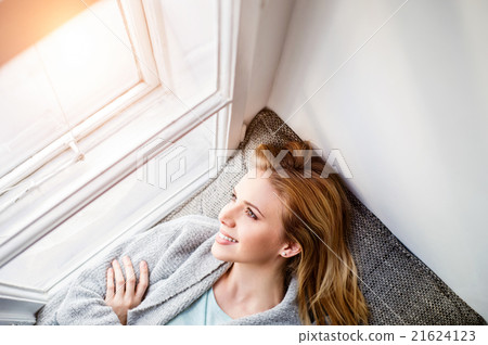 Woman lying on window sill, looking out of window Woman lying on window sill, looking out of window 21624123