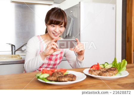 A young woman taking a picture of cooking 21628872