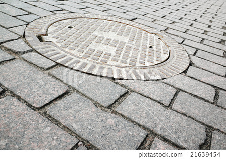 Round rusted hatch in urban cobblestone 21639454