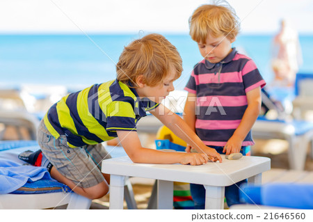 Two little kid boys playing on beach with stones Two little kid boys playing on beach with stones 21646560