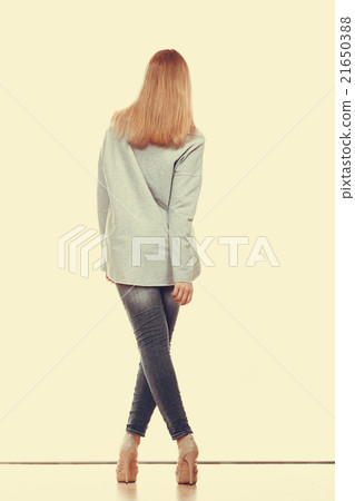 woman in denim pants high gray shirt back view woman in denim pants high gray shirt back view 21650388