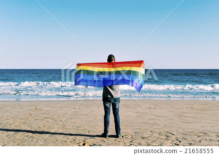 man with a rainbow flag in front of the ocean man with a rainbow flag in front of the ocean 21658555
