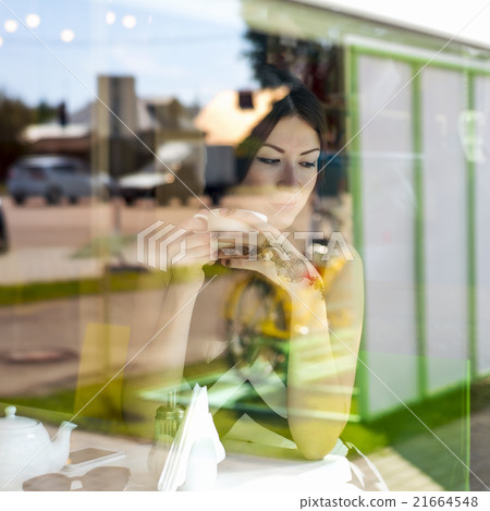 Young beautiful girl sits in cafe, sunny day 21664548