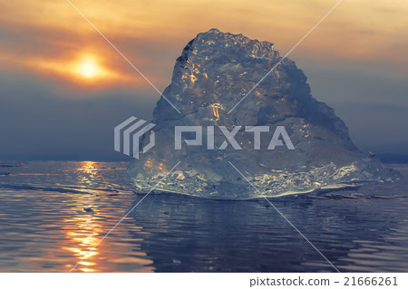 Transparent piece of ice on sunset sky background. 21666261