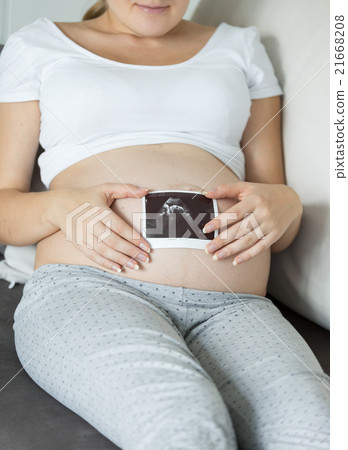 pregnant woman holding ultrasound image on stomach 21668208