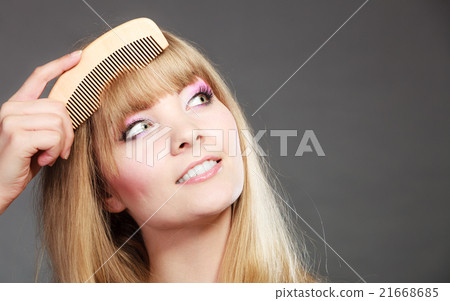 Closeup woman combing her fringe with comb Closeup woman combing her fringe with comb 21668685