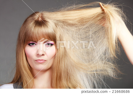 Blonde woman with her damaged dry hair. Blonde woman with her damaged dry hair. 21668686