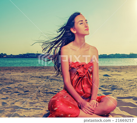 Long haired brunette meditate on sandy beach with Long haired brunette meditate on sandy beach with 21669257