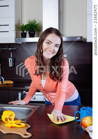 Attractive woman cleaning the counter in the kitchen Attractive woman cleaning the counter in the kitchen 21682475