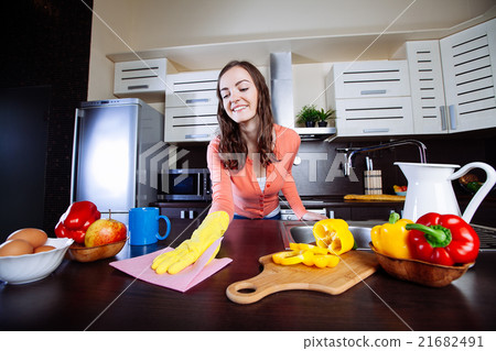Attractive woman cleaning the counter in the kitchen Attractive woman cleaning the counter in the kitchen 21682491