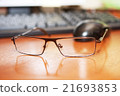 Glasses on front of keyboard and mouse 21693853