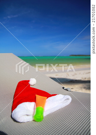 Santa Hat and sun tan on chaise longue 21701082
