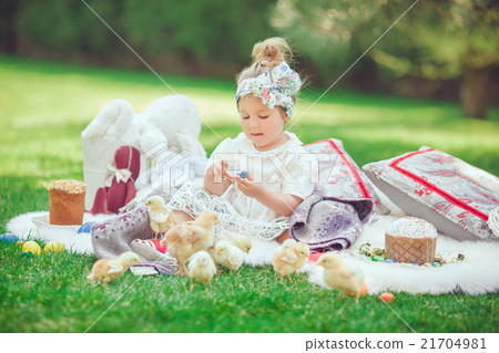 Happy child sits on a meadow looks to Easter 21704981