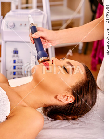 Relaxed young woman receiving electric facial Relaxed young woman receiving electric facial 21708984