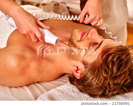 Young man receiving electric facial massage. Young man receiving electric facial massage. 21708991