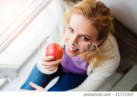 Woman on window sill holding fresh red apple 21715305