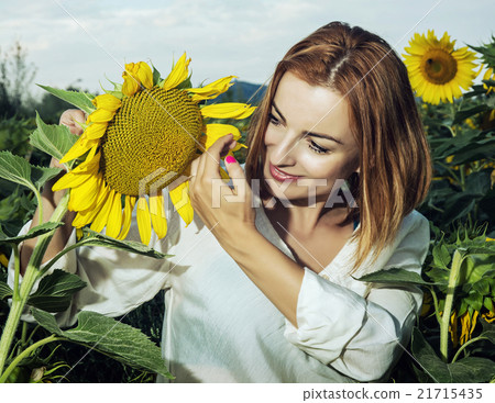 Pretty woman is standing by sunflower and look at it 21715435
