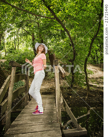 Young youful woman with sunhat posing on the wooden bridge 21715440