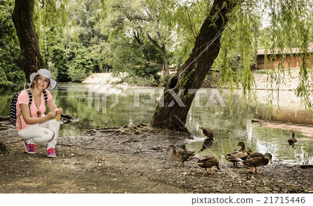 Young woman is feeding the group of duck in the city park Young woman is feeding the group of duck in the city park 21715446