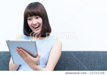 A young lady looking at the tablet and looking surprised A young lady looking at the tablet and looking surprised 21721139