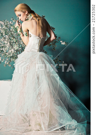 Bride in wedding dress behind bush with flowers Bride in wedding dress behind bush with flowers 21725302