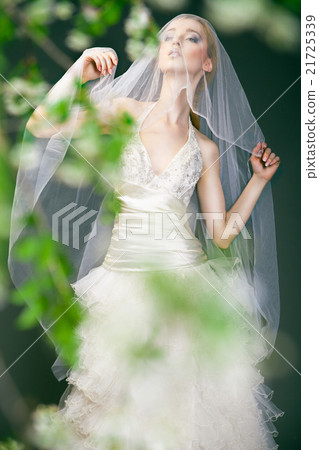 Bride in wedding dress behind bush with flowers Bride in wedding dress behind bush with flowers 21725339