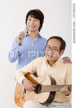 Senior men playing guitar and senior women singing with microphone Senior men playing guitar and senior women singing with microphone 21726220