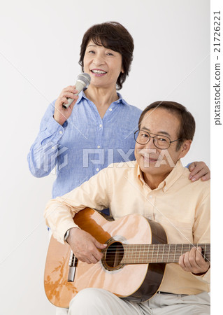 Senior men playing guitar and senior women singing with microphone Senior men playing guitar and senior women singing with microphone 21726221