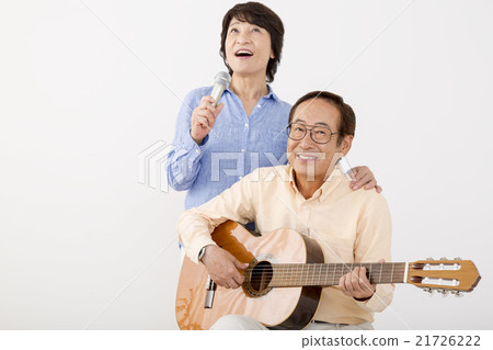 Senior men playing guitar and senior women singing with microphone Senior men playing guitar and senior women singing with microphone 21726222