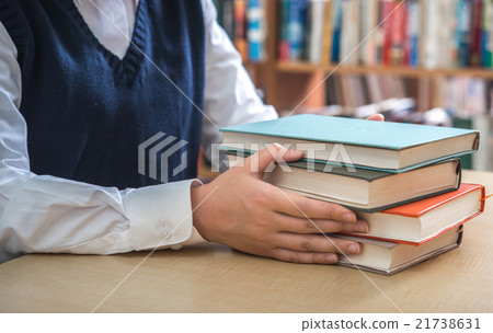 A female student holding a book in the library A female student holding a book in the library 21738631