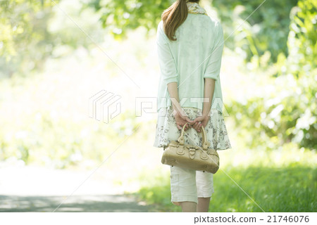 A rear view of a woman walking in the fresh green 21746076
