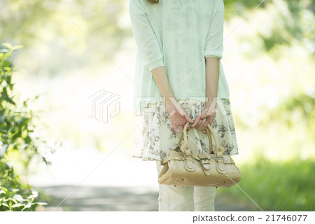 A rear view of a woman walking in the fresh green 21746077