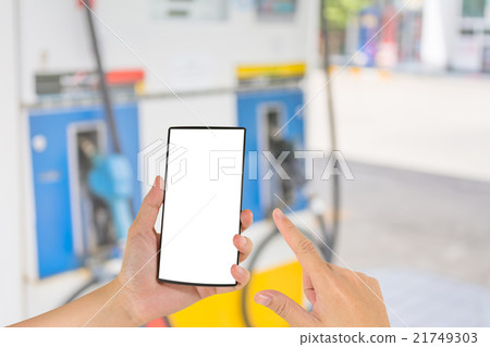 hand holding smart phone and gas station in background. hand holding smart phone and gas station in background. 21749303
