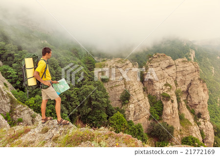Backpacker with a map on the mountains Backpacker with a map on the mountains 21772169