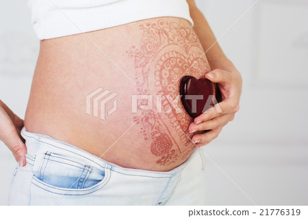 Red heart on pregnant belly with henna tattoo  21776319