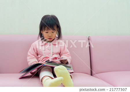 A child watching a picture book on a pink sofa A child watching a picture book on a pink sofa 21777307