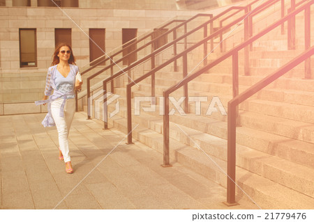 Businesswoman walking near office building Businesswoman walking near office building 21779476