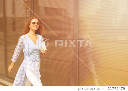 Businesswoman walking near office building Businesswoman walking near office building 21779479