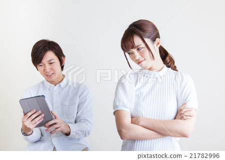 A woman looking at a tablet jealous of a man 21782996