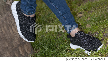Feet in sneakers in green grass 21789211