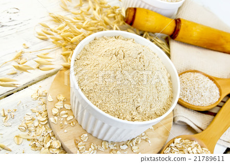 Flour oat in white bowl with flakes on light board 21789611