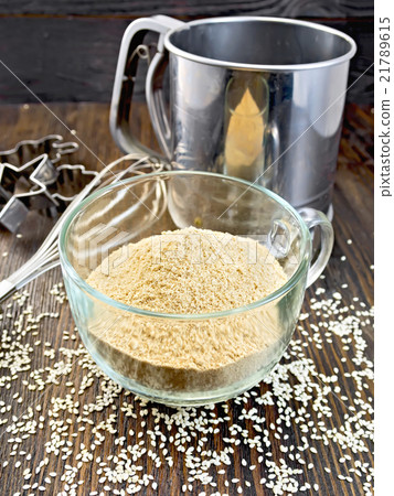 Flour sesame in cup with sieve on dark board 21789615