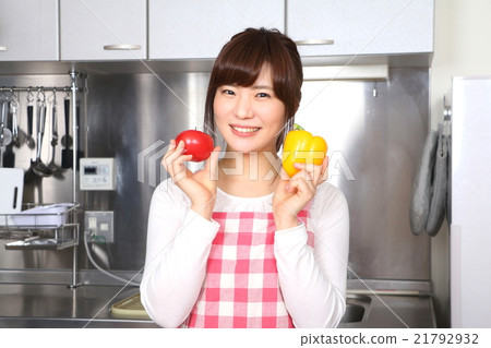 A woman holding a vegetable in the kitchen A woman holding a vegetable in the kitchen 21792932