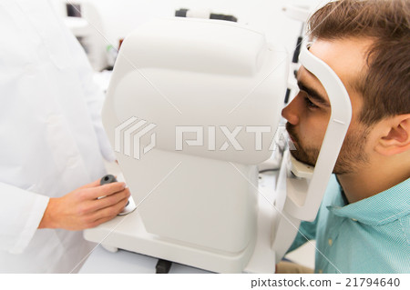 optician with autorefractor and patient at clinic 21794640