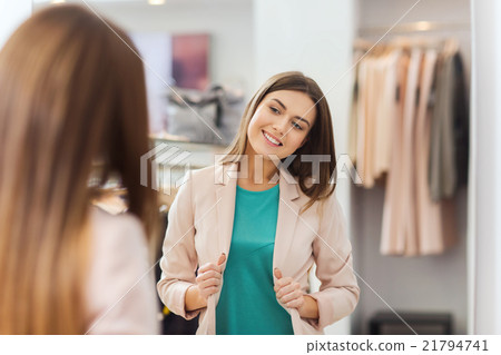 happy woman posing at mirror in clothing store 21794741