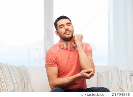 unhappy man suffering from pain in hand at home 21794888