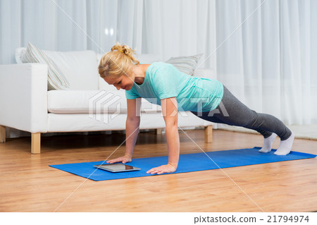 woman with tablet pc doing plank exercise at home 21794974